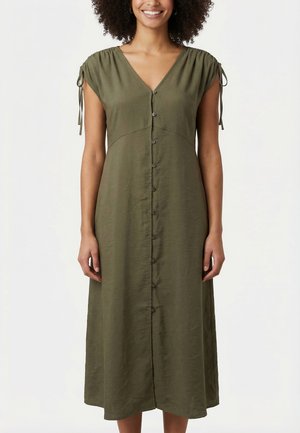 Femme portant une robe midi vert olive avec manches courtes à nouer et fermeture boutonnée à l'avant, souriante devant un fond blanc uni.