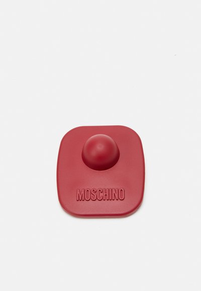 Accesoriu din silicon roșu cu vârf rotunjit și bază pătrată. "MOSCHINO" embosat pe marginea inferioară. Textură netedă pe toată suprafața.