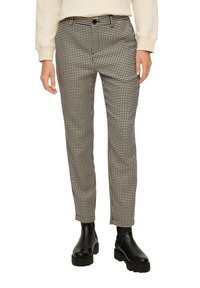 Zwart-witte broek met houndstooth patroon, met een getailleerde pasvorm en enkel lengte, gemaakt van geweven stof. Gecombineerd met zwarte enkellaarsjes.