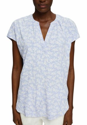 Blouse florale bleu clair à manches courtes, décolleté en V, en tissu doux, avec un motif floral blanc subtil et une coupe fluide pour plus de confort.