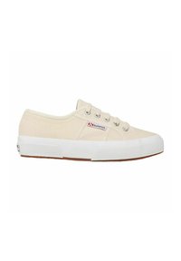Zapatillas de lona en beige con suela de goma blanca, cinco ojetes plateados y un pequeño logo rojo y azul en el costado. Superficie texturizada.