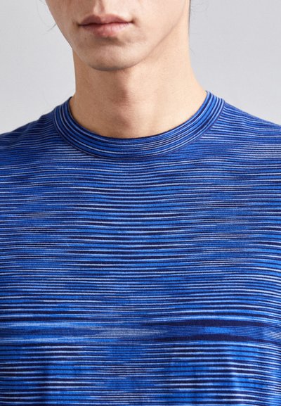 T-Shirt azul às riscas com mangas curtas e decote redondo. Apresenta tonalidades variadas de azul e uma textura suave, realçando as linhas horizontais.