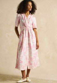 Ceļa garuma, pogu kreklis mīkstā audumā ar rozā un baltu toile rakstu, ar pieguļošu vidukli un īsām piedurknēm; apvienots ar krēmkrāsas loafers.