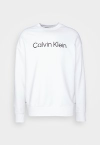 Witte sweatshirt met geribbelde manchetten en zoom, gekenmerkt door een zwart 'Calvin Klein' logo op de voorkant. Eenvoudig ontwerp met ronde hals en een gladde textuur.