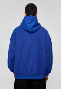 Hoodie in helderblauw, met een gemêleerde stof, oversized pasvorm, en ribbelmanchetten en -zoom voor extra comfort.