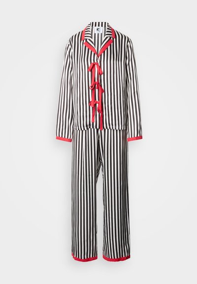 Set de pijamale alb-negru cu dungi și accente roșii, având o jachetă cu nasturi cu trei benzi de panglică și pantaloni evazați asortați.