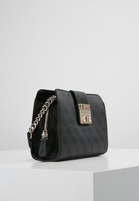 Sort faux læder håndtaske med guldfarvet hardware, kædestrop og mærketlås. Tekstureret overflade med subtilt præg. 