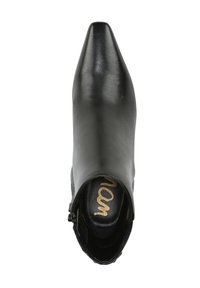 Bottine en cuir noir avec bout pointu, fermeture éclair latérale, texture lisse et logo doré contrastant sur la semelle intérieure.