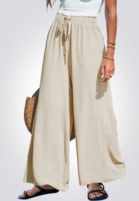 Pantalones de pierna ancha en color beige con cinturilla elástica y cordón. Textura ligera y suave con un diseño fluido y un movimiento sutil.