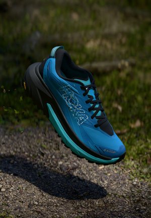 Blue running shoe with a lightweight mesh upper, black accents, Vibram outsole, and prominent logo. Features a cushioned midsole and laces.