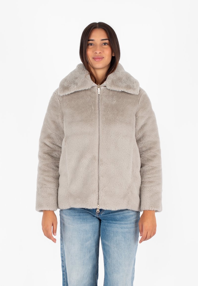 Giacca in pelliccia sintetica grigia con colletto ampio e chiusura con zip, caratterizzata da una consistenza morbida e una vestibilità leggermente più ampia, abbinata a jeans blu.