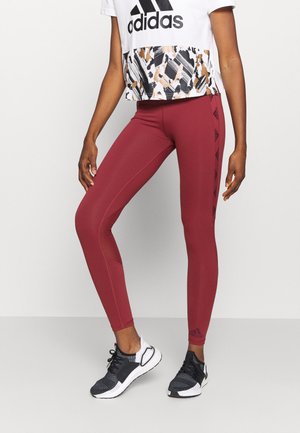 Leggings bordeaux au design ajusté, avec des accents noirs contrastants et un logo. Associés à un crop top blanc avec un ourlet à motifs.