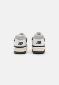 White and gray sneakers with a cushioned collar, textured suede accents, thick rubber soles, and a black logo on the heel.