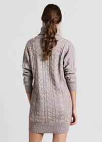 Vestito maglione a trecce in beige morbido, con collo alto, maniche lunghe e polsini a costine, caratterizzato da un motivo testurizzato su tutta la superficie.