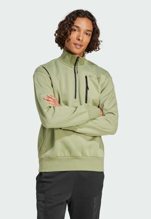 Pull vert clair avec col montant, poche zippée sur la poitrine gauche, manches longues et ourlet côtelé. Fabriqué en matériau doux et texturé.