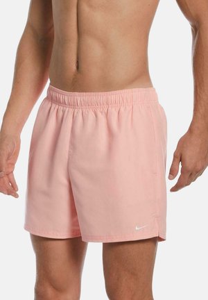 Bañadores de color rosa claro con una tela transpirable, cinturilla elástica y bolsillos laterales. Presenta un pequeño logo blanco de Nike cerca del dobladillo.