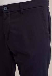Pantaloni din bumbac bleumarin, cu o textură fină, având închidere cu un buton, buzunare laterale și brâie pentru curea la talie.