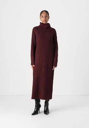 Burgundy knit turtleneck dress with ribbed texture, long sleeves, and a straight silhouette, paired with black high-heeled boots.