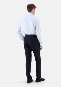 Hellblaues Hemd mit Kragen und dunkelblaue Hose. Die Hose hat Gesäßtaschen; das Hemd verfügt über geknöpfte Manschetten und eine klassische Passform.