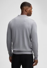 Grau langärmliges Poloshirt aus strukturiertem Strick, mit ribbeltem Kragen und Bündchen. Mit einer taillierten Silhouette und einfarbigem Design.