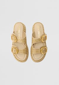 Woven straw sandals with two wide straps, featuring gold-tone buckles. Light tan sole with padded footbed, offering casual, open design.