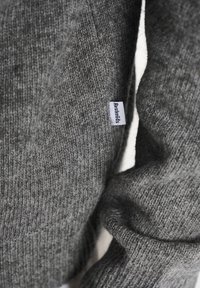 Šedý pletený svetr s měkkou strukturou. Má vzor připomínající denim a malou bílou visačku s nápisem "Restirations."