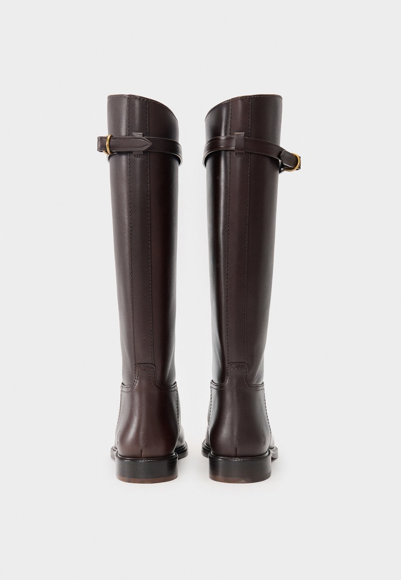 Wysokie ciemnobrązowe skórzane kozaki z regulowanymi paskami w okolicy kostki i małymi złotymi klamrami, widziane z tyłu na białym tle.