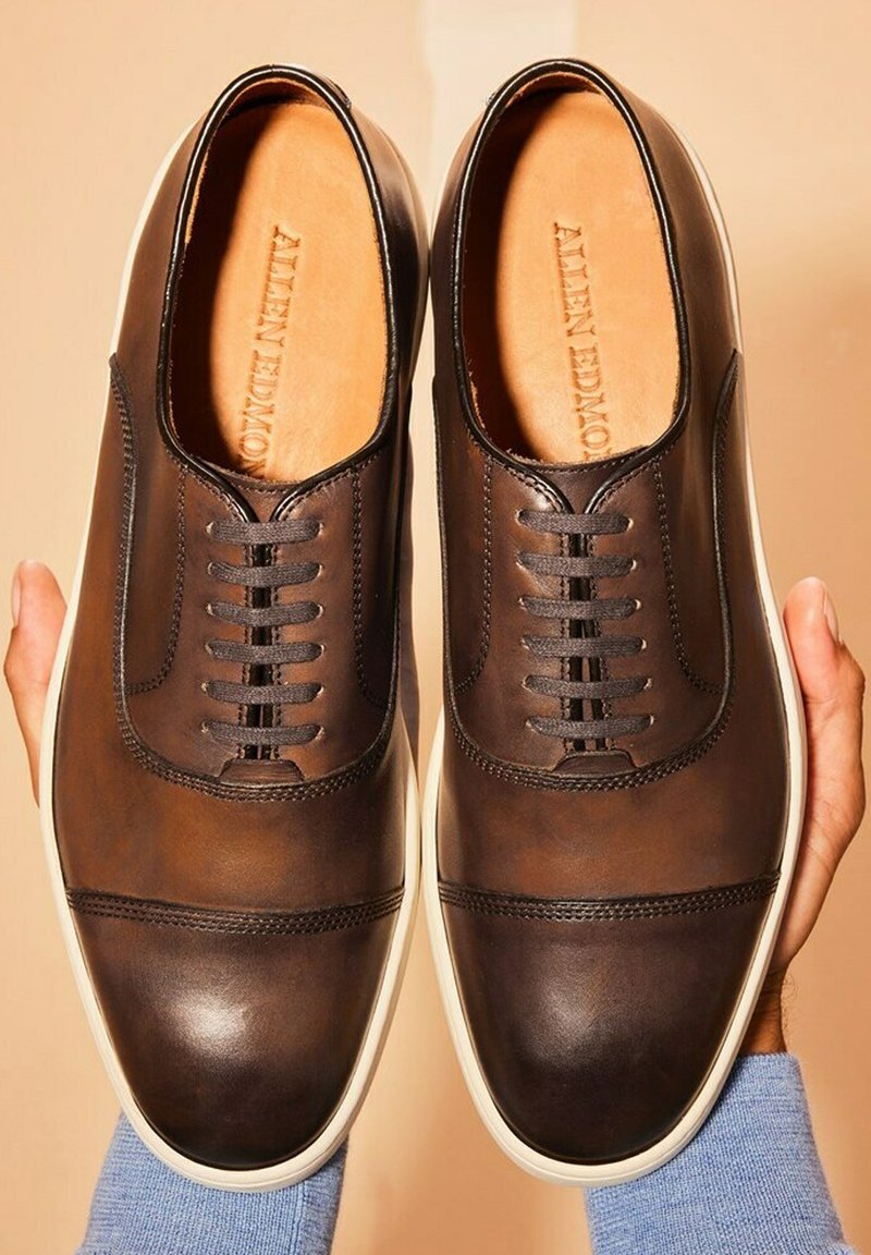 Bruine leren schoenen met een ronde neus, voorzien van een 5-oog veterontwerp, witte rubberen zool en subtiele stiksels.