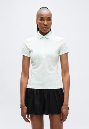 Mintgrønn polotrøye med et subtilt sikksakkmønster, korte ermer og en klassisk krage, kombinert med en svart plissert skjørt.