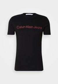Černé bavlněné tričko s krátkým rukávem, na přední straně s červeným logem "Calvin Klein Jeans". Kulatý výstřih, standardní střih.