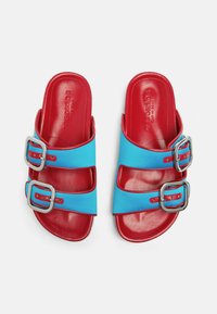 Svijetloplavi i crveni sandali s dva široka remena koji imaju srebrne kopče. Glatki gornji materijal i sjajna teksturirana unutrašnjost.