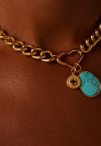 Gouden ketting met een hartvormige sluiting, verfraaid met een turquoise stenen hanger en een kleine ronde bedel met een ster.