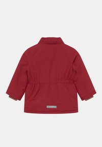 Veste rouge imperméable avec une taille cintrée, des manches longues, et un petit détail réfléchissant à l'arrière. Intérieur avec une doublure texturée.