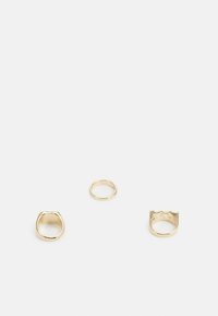 Conjunto de três anéis: duas alianças de ouro lisas e um anel de ouro com uma borda texturizada e ondulada. Todos apresentam um acabamento metálico brilhante.