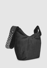 Schwarze Schultertasche aus weichem Samt. Verfügt über einen breiten Trageriemen mit einem weißen Tropfenmuster. Abgerundete Form mit gerafftem oberen Bereich.