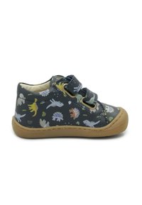 Scarpe in tessuto nero con motivi di dinosauri colorati, due cinturini in Velcro e una suola in gomma marrone con superficie zigrinata.