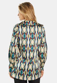 Blusa estampada con cuello, que presenta formas de diamante en azul, verde, rojo y crema. Mangas largas abullonadas y un corte relajado.