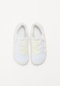White athletic shoes with a mesh upper, featuring elastic straps, a BOA fastening system, and a textured rubber outsole.