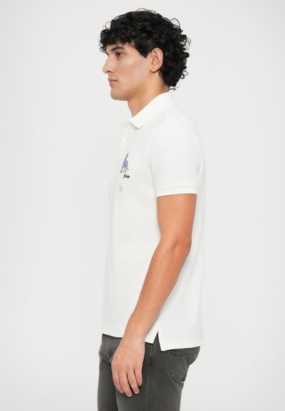 Camisa polo branca com colarinho, mangas curtas e aberturas nas laterais. Apresenta um logo azul bordado no peito. Material de algodão macio.
