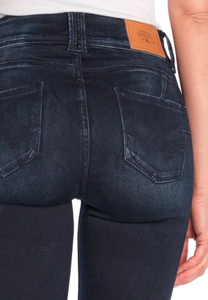 Donkerdenim jeans hebben een hoge taille, een slanke pasvorm, zichtbare stiksels en twee achterzakken met een kenmerkend yoke-ontwerp. Tan leren label op de tailleband.