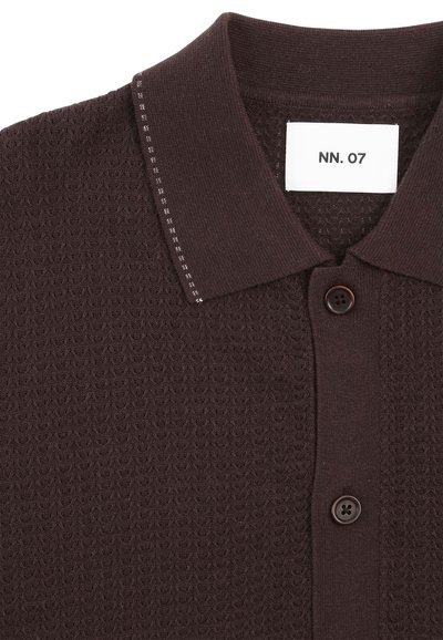Dunkelbraunes Strick-Poloshirt mit strukturiertem Muster, zwei Knöpfen und einem weißen Etikett mit der Aufschrift "NN. 07" im Kragen.