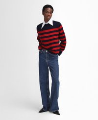 Gestreifter Pullover in Rot und Marineblau mit langen Ärmeln, kombiniert mit hochtaillierten, ausgestellten Jeans aus Denim. Schwarze Pumps mit spitzem Absatz runden das Outfit ab.