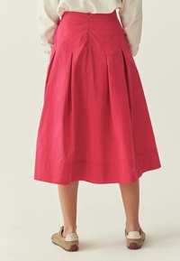 Roosa volditud seelik, millel on vormitud vöökoht ja lukuga sulgur. Kangas on sileda tekstuuriga ja langeb keskmise sääre pikkuseni.