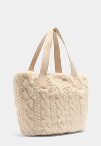 Sac fourre-tout en fausse fourrure beige avec un motif en tricot câble texturé, doté de poignées en cuir lisse et d'un extérieur doux et pelucheux.