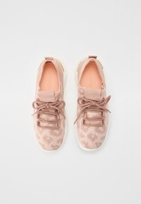 Różowe sportowe trampki z fakturowanym wierzchem, z delikatnym wzorem, sznurowane, z białą podeszwą. Wnętrze w jasnym brzoskwiniowym kolorze.