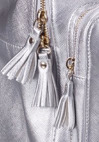 Borsa a tracolla con texture argentata, dotata di doppie cerniere con finiture dorate e nappine in pelle bianca per un tocco di eleganza.