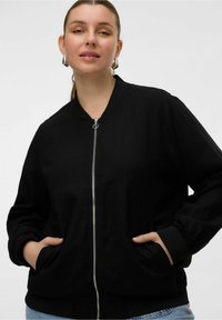 Czarna kurtka bombowca z zamkiem z przodu, kieszeniami bocznymi i ściągaczami na mankietach. Wykonana z gładkiego materiału o eleganckim, minimalistycznym wzornictwie.