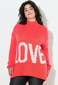 Fuchsia Übergröße Pullover mit hohem Kragen und lockeren Ärmeln, der ein auffälliges weißes "LOVE" Strickdesign auf der Vorderseite zeigt.