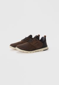 Des chaussures en cuir marron avec des accents noirs, dotées d'une semelle crème flexible, de lacets et d'une languette au talon pour un enfilage facile.