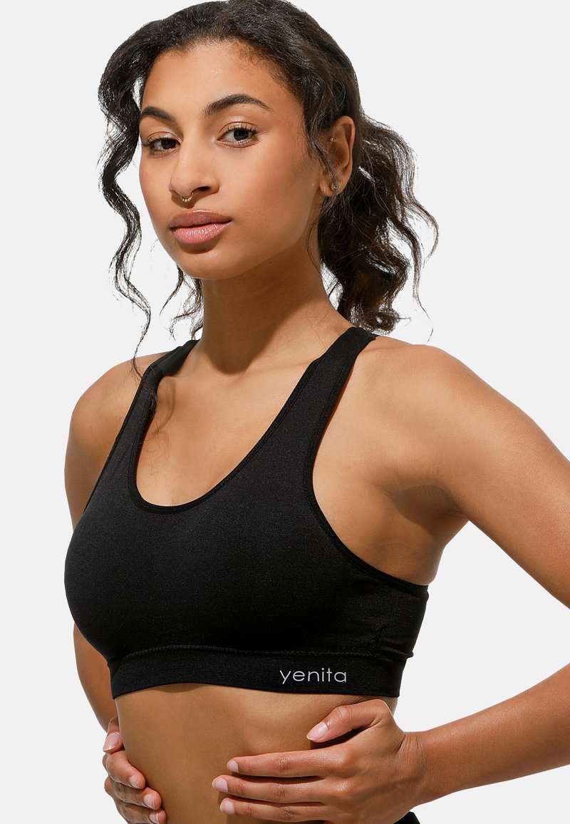 Reggiseno sportivo nero con scollo rotondo, spalline larghe e una texture liscia; presenta il nome del marchio "yenita" ricamato sull'orlo.